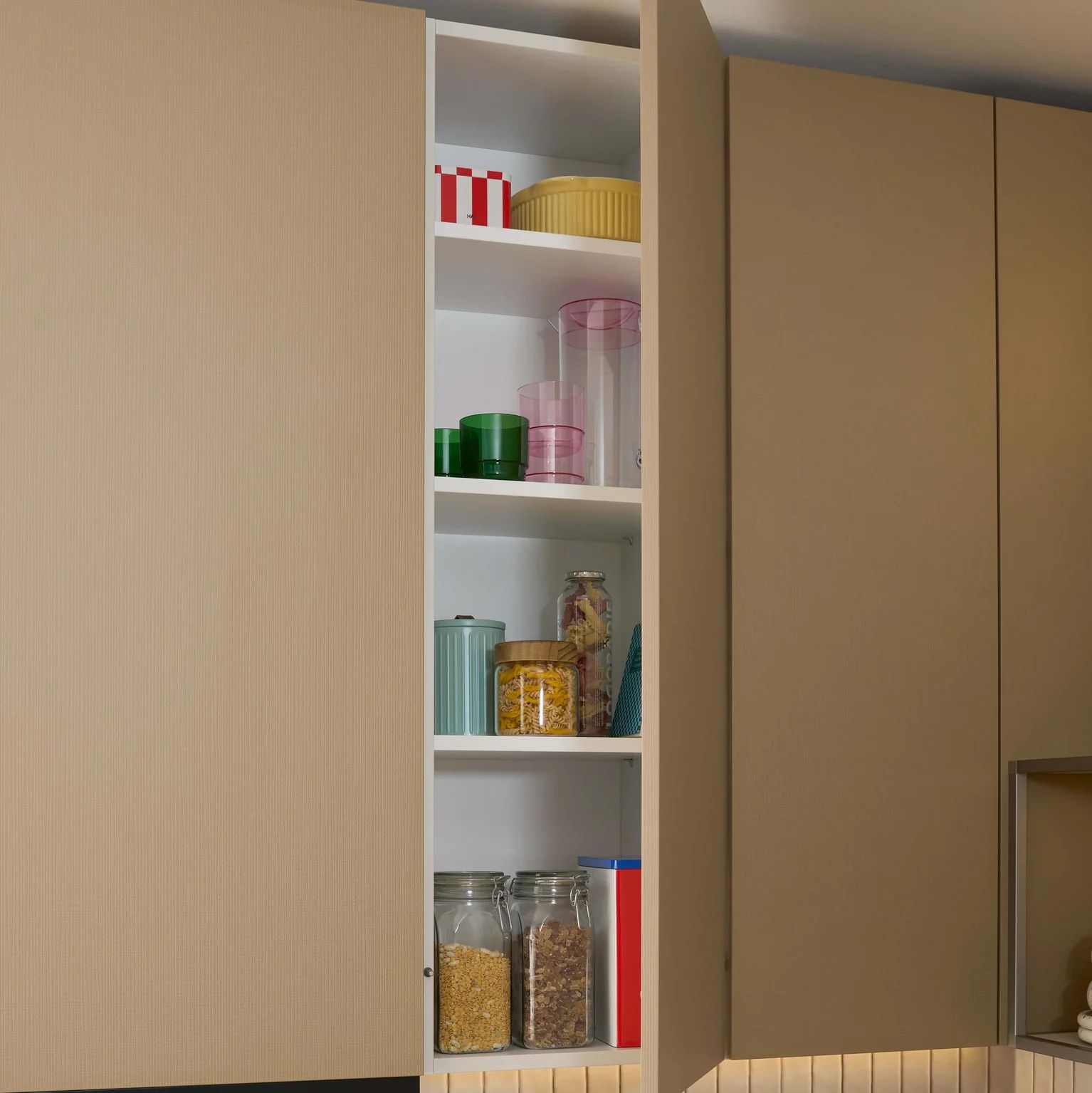 Schüller Neuheiten 2027 geöffneter Schrank in Sora Caramel Struktur mit Vorräten